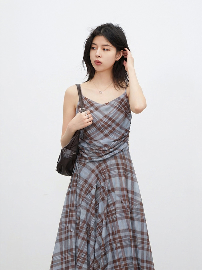 Model wearing a plaid sleeveless dress with a fitted bodice and flowing skirt
