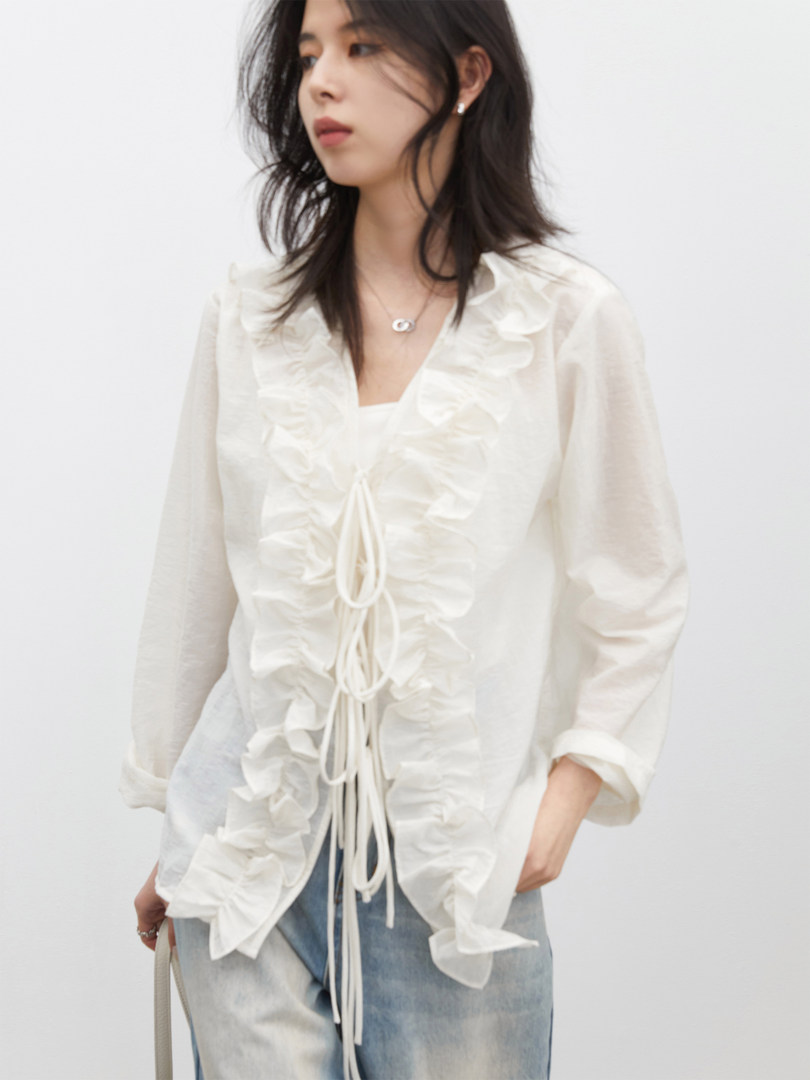 Model wearing a white sheer ruffled tie-front blouse