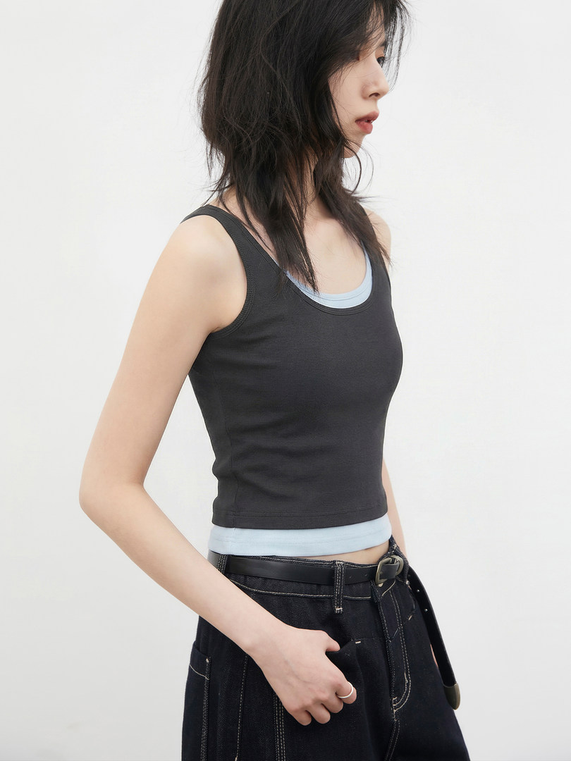 Black sleeveless tank top layered over a light blue camisole on a model