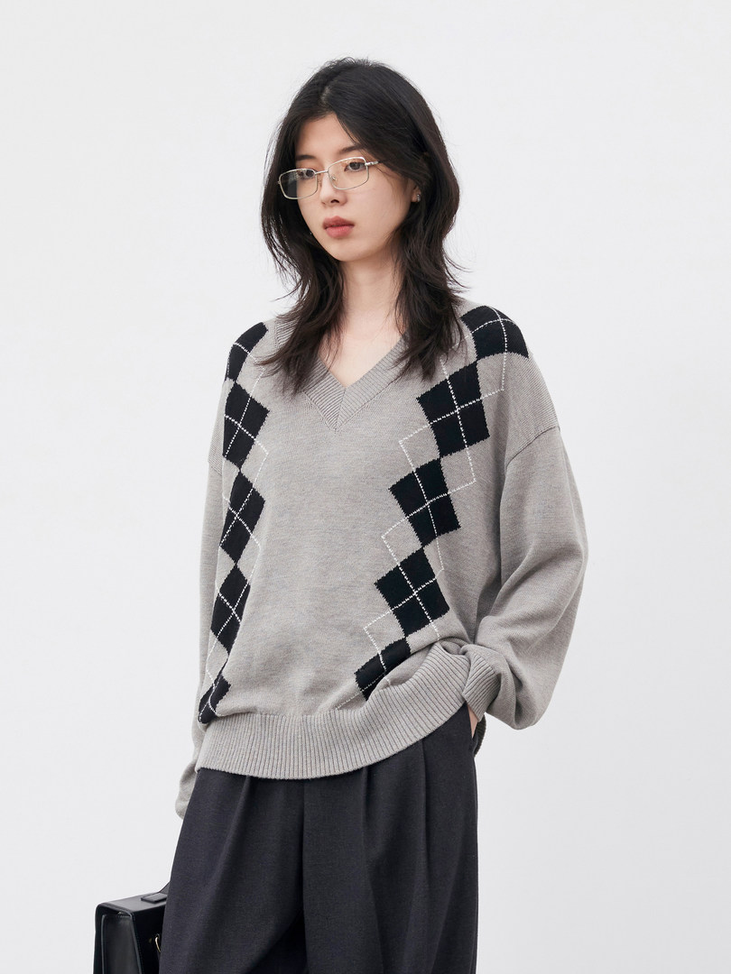 Model wearing a gray argyle knit sweater with black diamond pattern