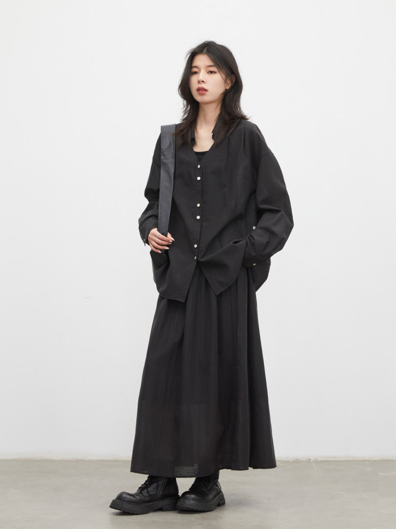 Model wearing a black oversized button-up shirt with a long skirt and black boots