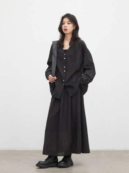 Model wearing a black oversized button-up shirt with a long skirt and black boots