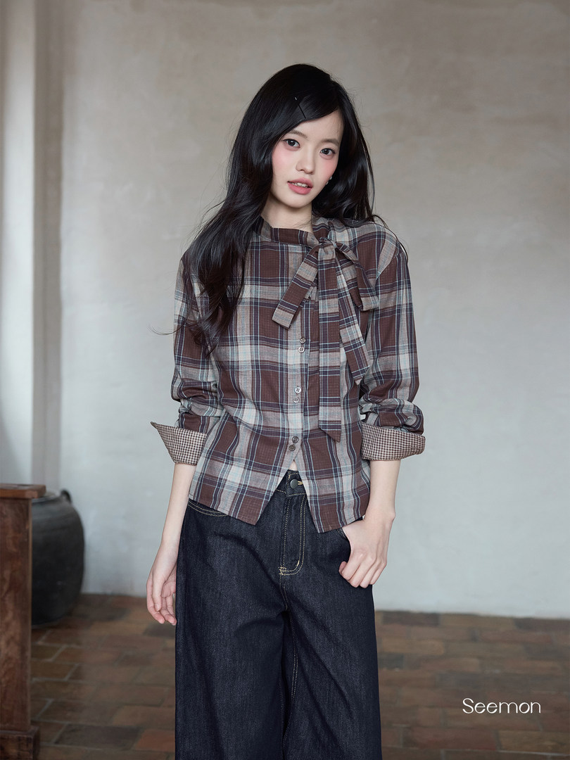 Model wearing a brown plaid bow-tie blouse with dark jeans