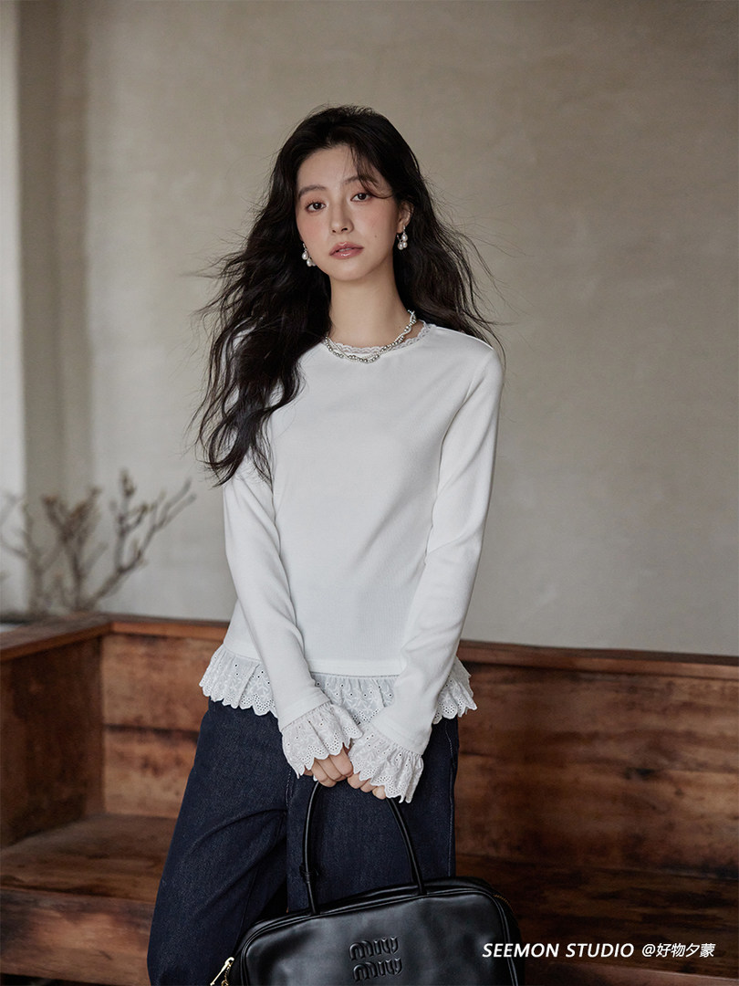 Model wearing a white long-sleeve blouse with lace trim cuffs and hem