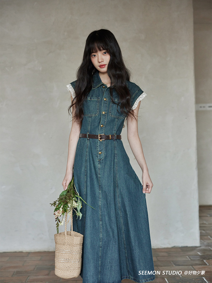 Model wearing a sleeveless denim dress with a belt and lace-trimmed sleeves