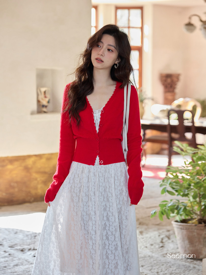 Woman wearing a red cardigan over a white lace dress
