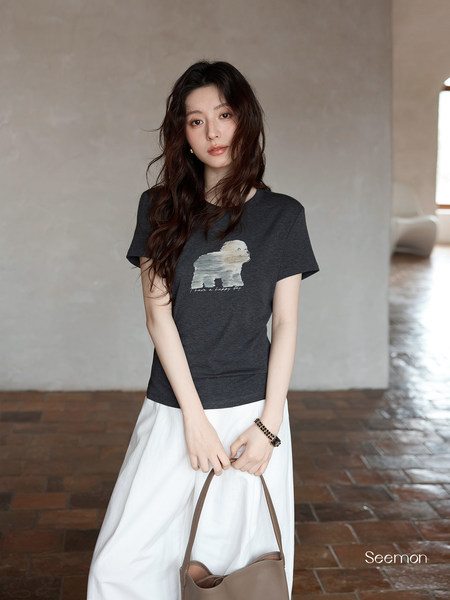 Model wearing a dark graphic T-shirt with a white skirt and handbag