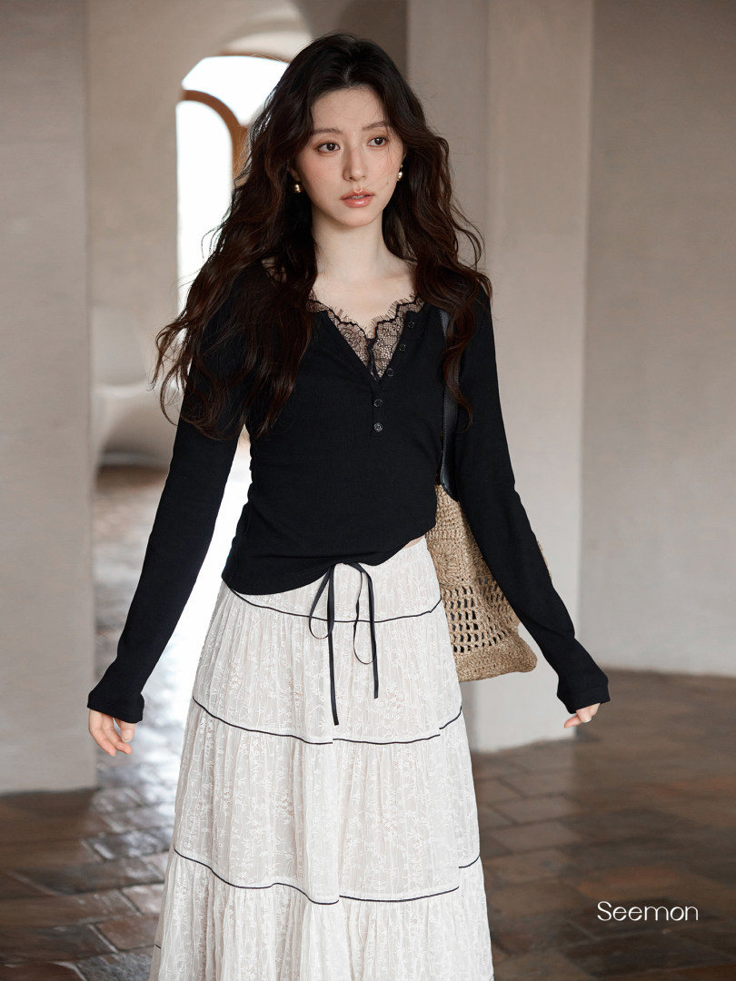 Model wearing a black lace-trim top with a white tiered skirt