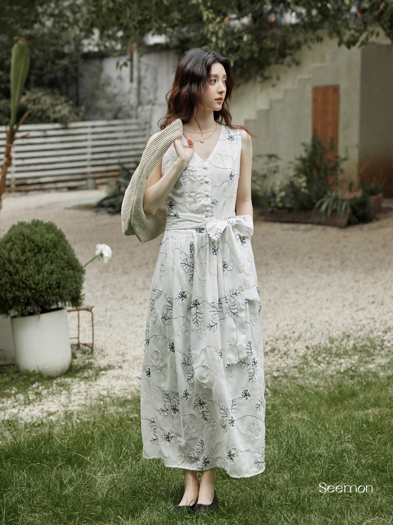 White embroidered sleeveless midi dress worn by a model outdoors
