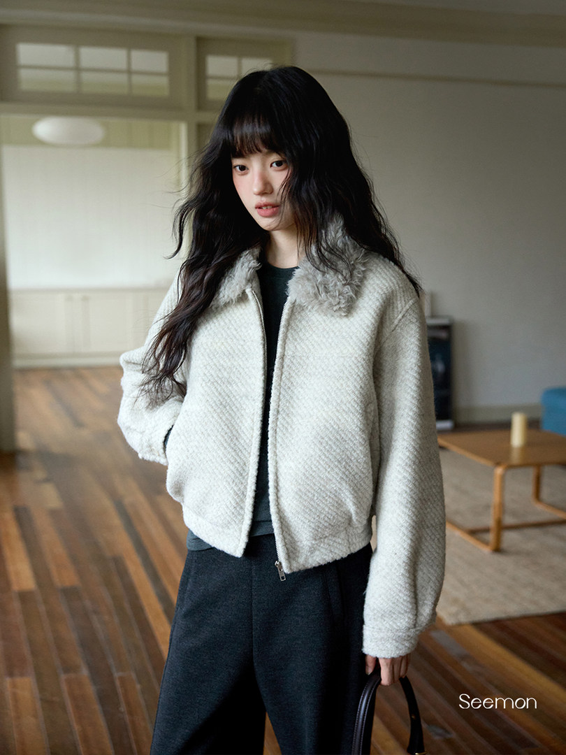 Model wearing a light gray fuzzy zip-up jacket indoors