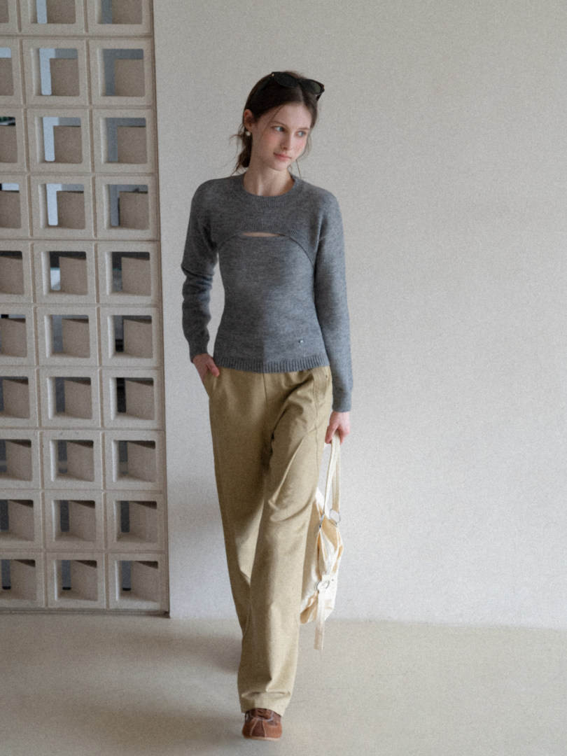 Model wearing a gray knit sweater with beige pants and a light tote bag