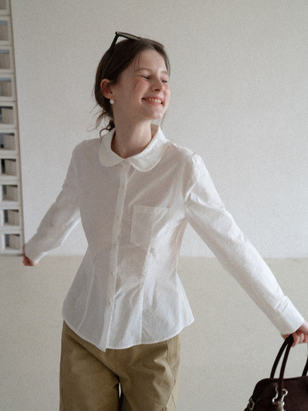 Woman wearing a white button-up shirt with a rounded collar