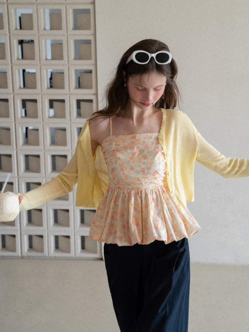 Model wearing a floral peplum camisole top with a yellow cardigan and dark pants