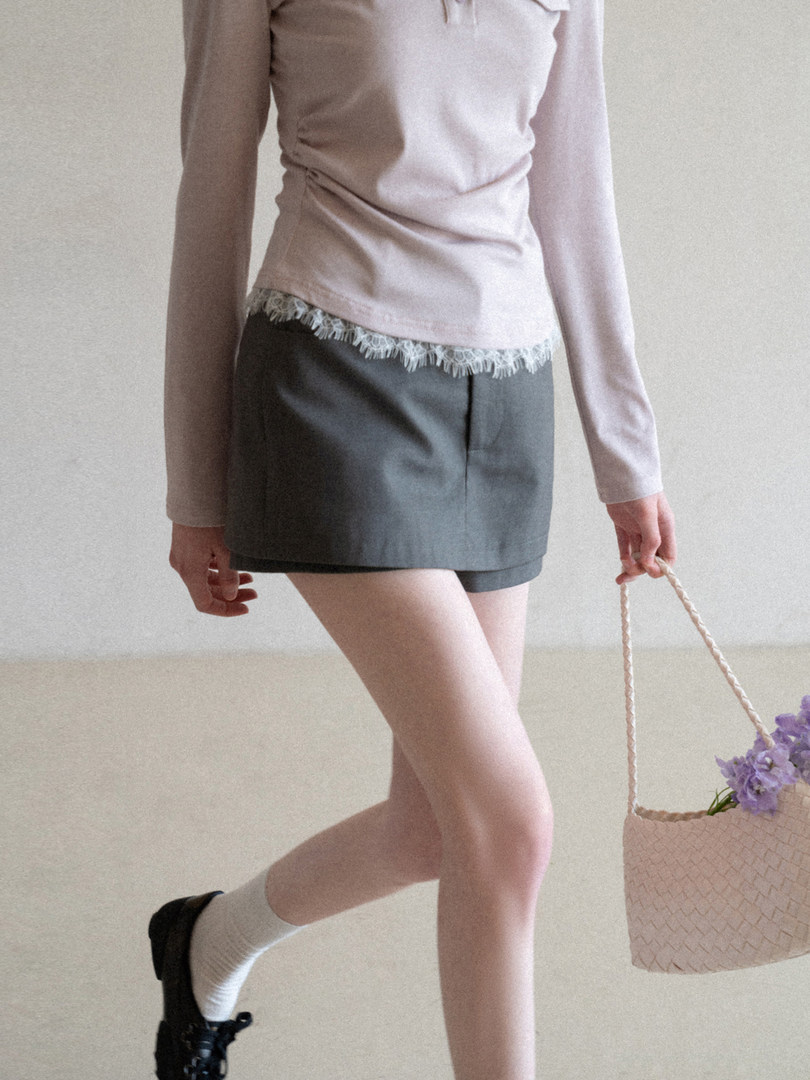 Model wearing a light long-sleeve top and gray shorts with a tote bag