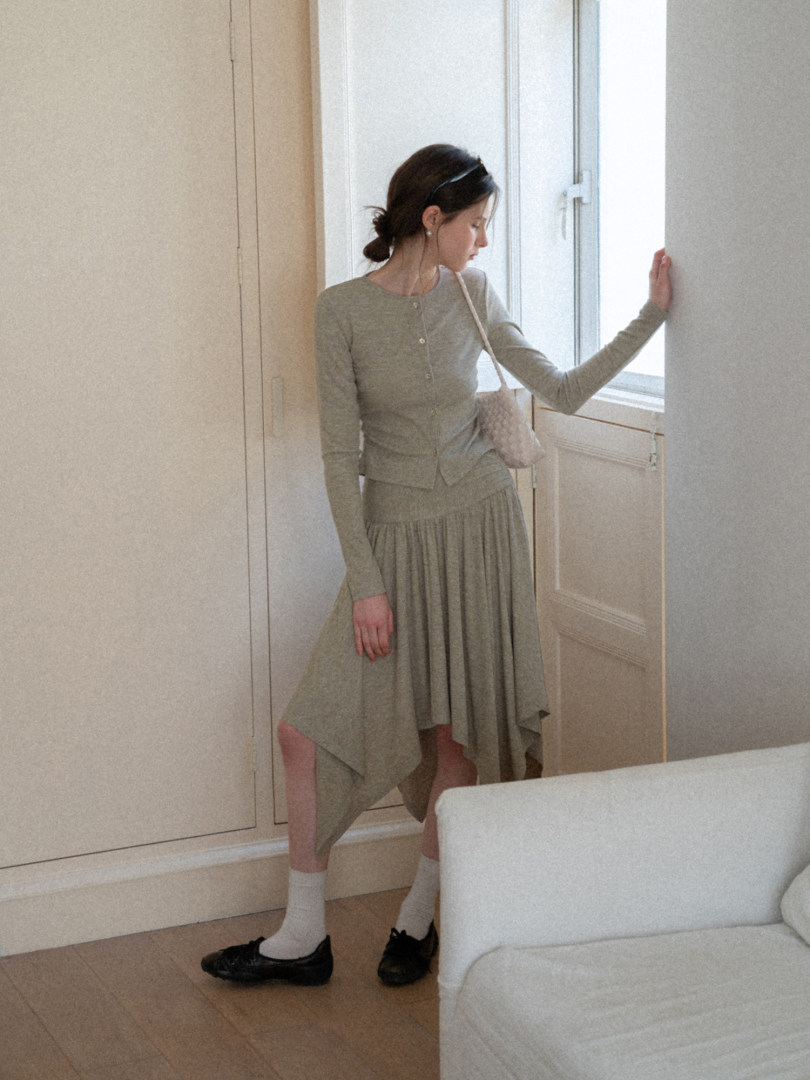 Woman modeling a gray knit top and asymmetrical skirt outfit