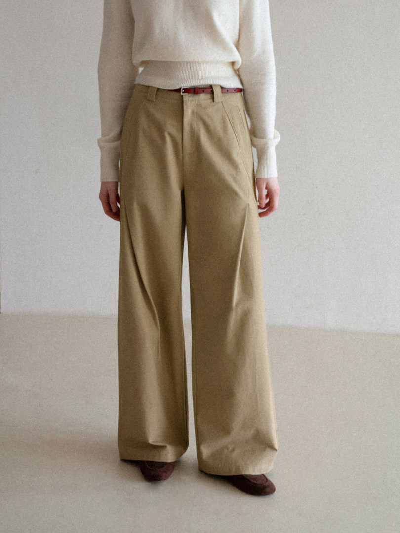 Model wearing beige wide-leg trousers with a cream sweater and red belt