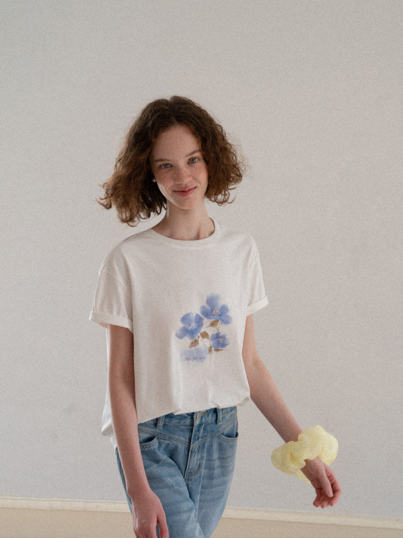Model wearing a white floral graphic T-shirt with light blue jeans