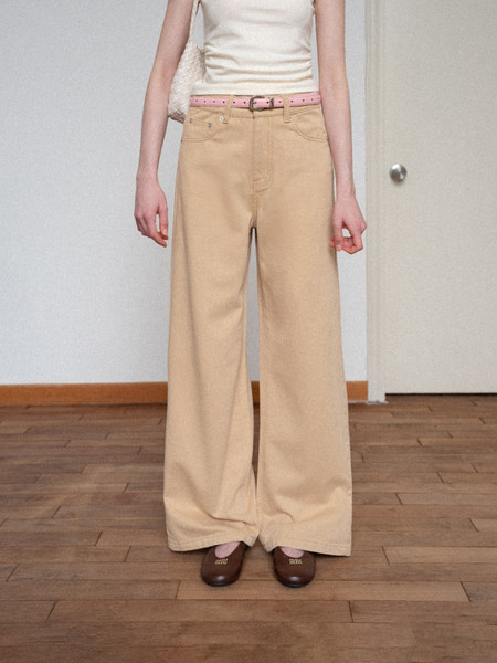 Model wearing beige wide-leg trousers with a pink belt and brown flats
