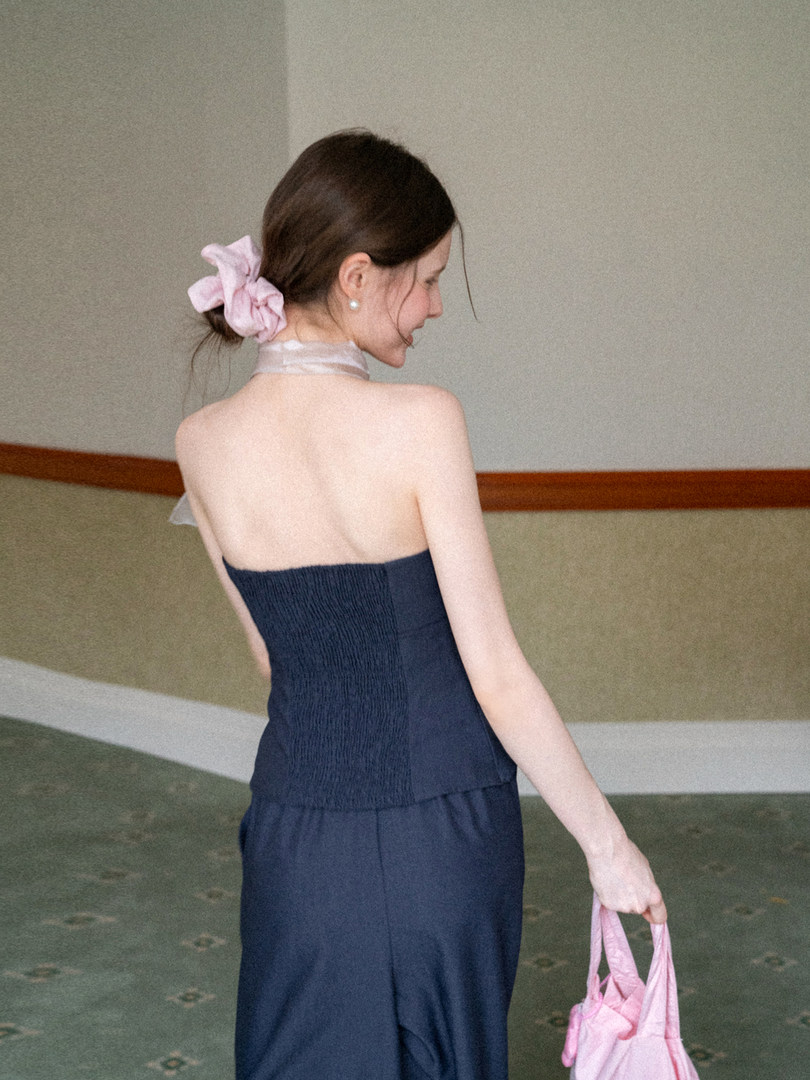 Model wearing a dark strapless dress with a sheer neck scarf and pink accessories