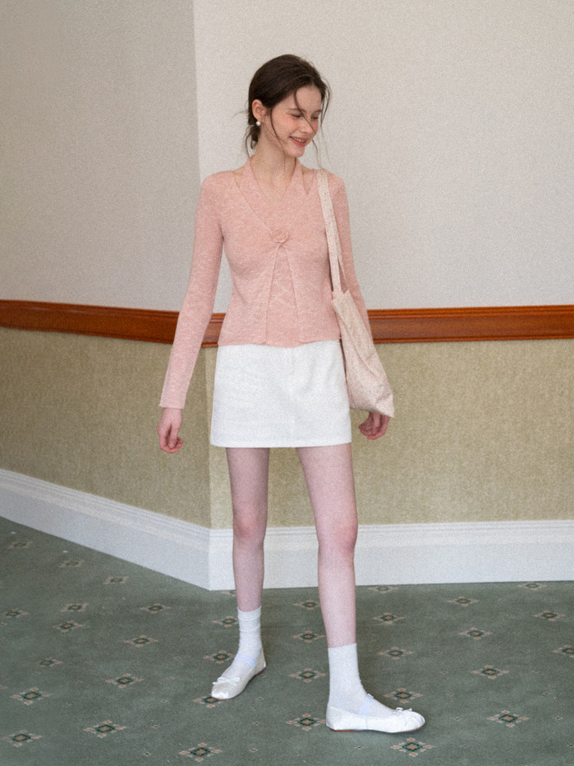 Model wearing a pink long-sleeve top with a white mini skirt and white flats