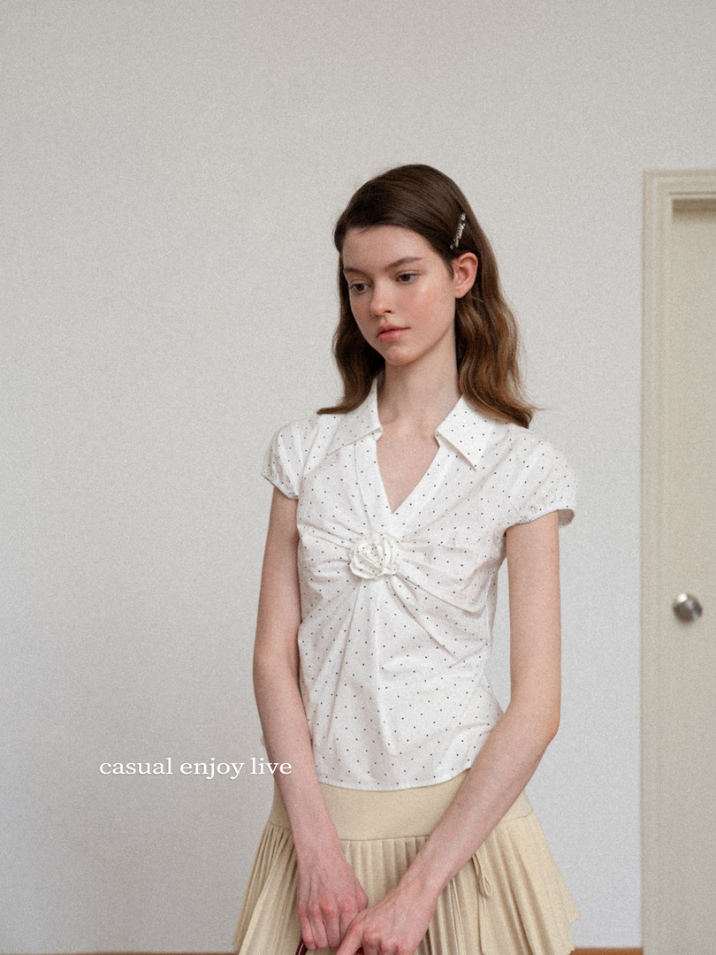 Model wearing a white polka dot short-sleeve blouse with a beige pleated skirt