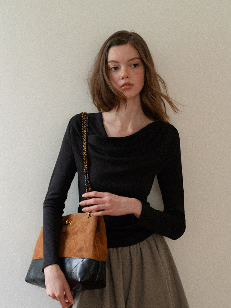 Model wearing a black long-sleeve top with a tan and black quilted shoulder bag