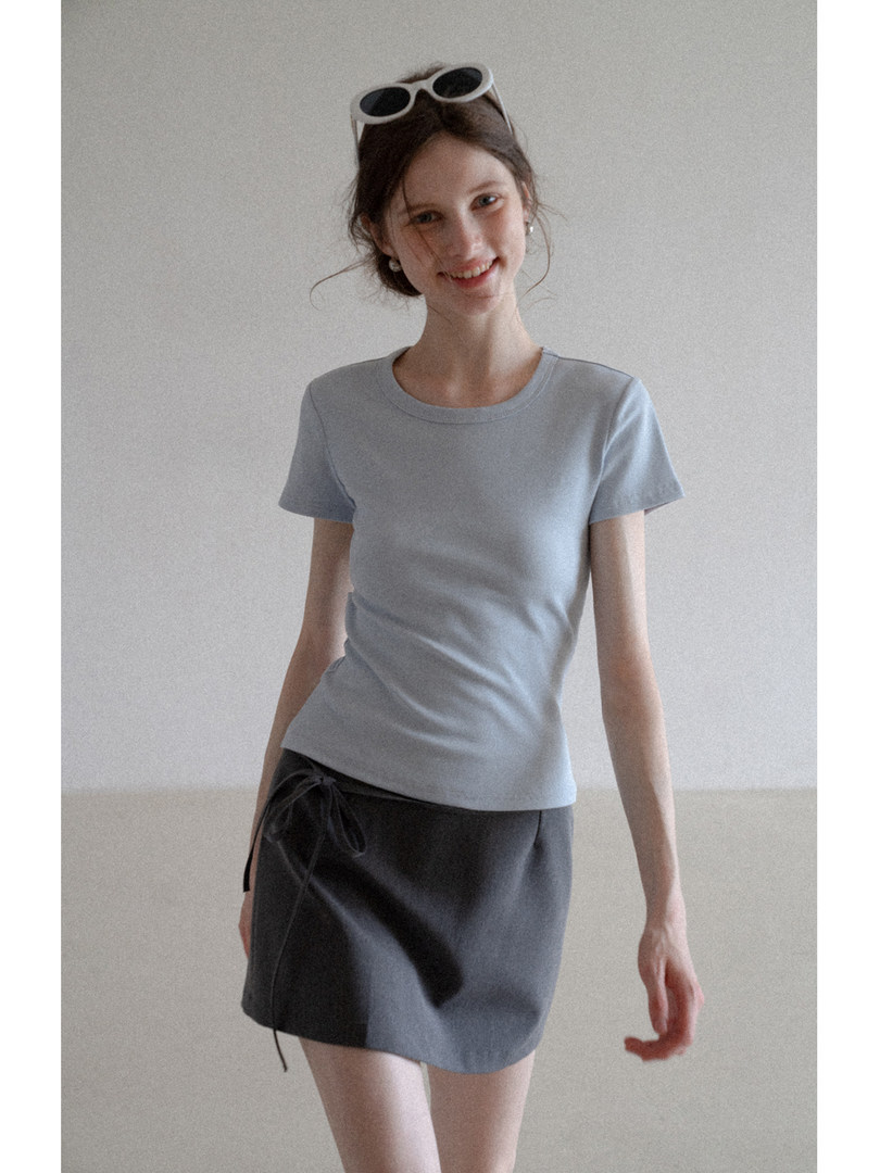 Woman modeling a light blue short-sleeve top with a dark wrap skirt