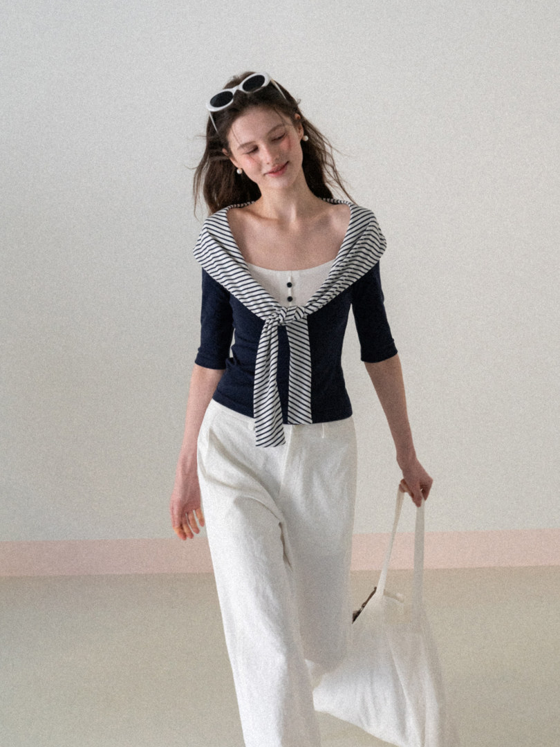 Model wearing a navy and white striped sailor-style top with white pants