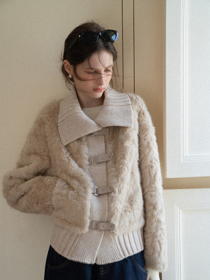 Model wearing a beige faux-fur coat over a chunky knit sweater