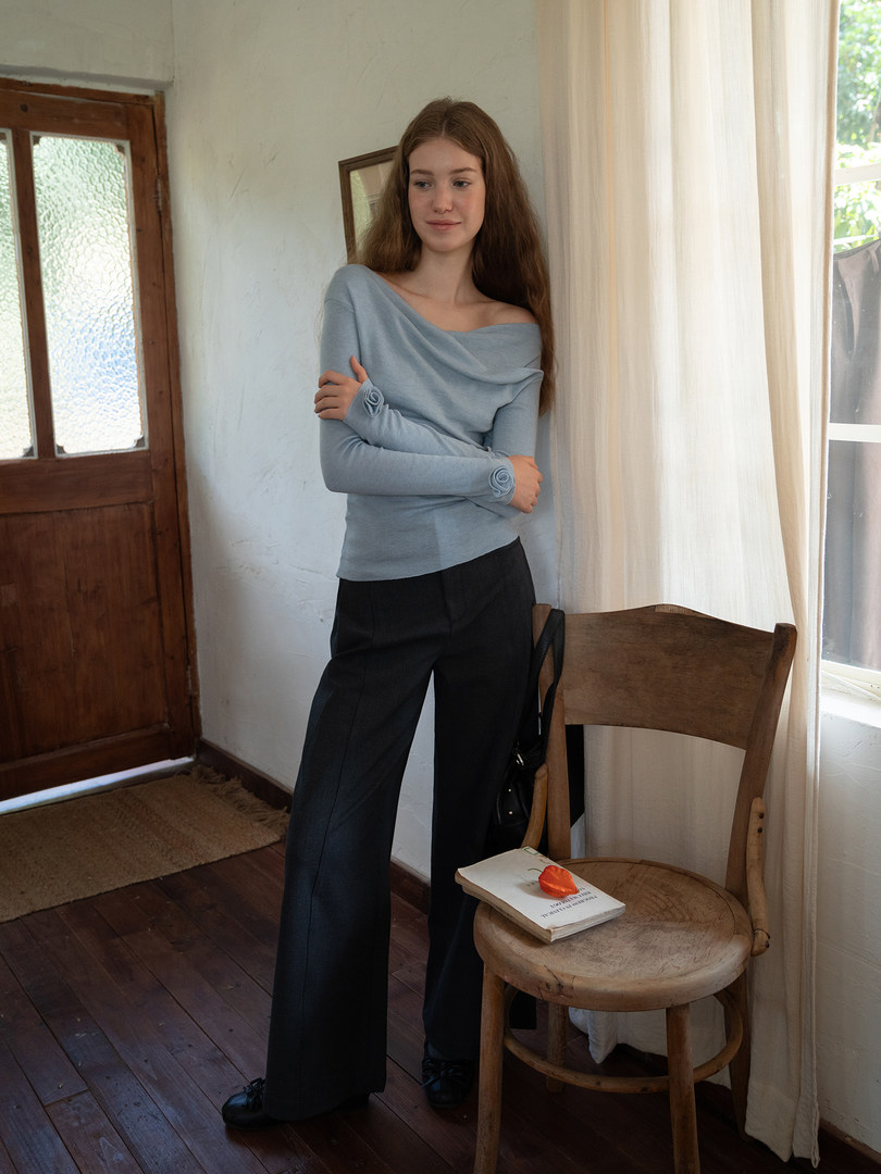 Model wearing a light blue off-shoulder long-sleeve top with black wide-leg pants