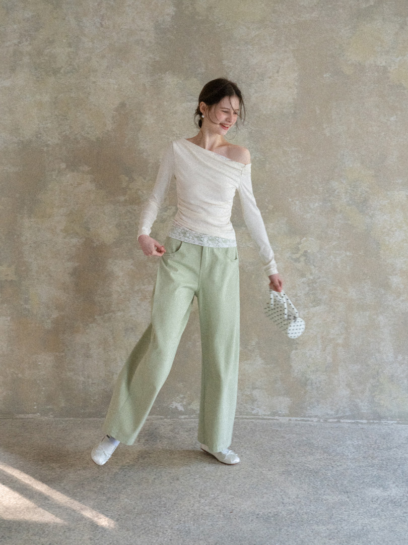 Model wearing a white off-shoulder top and light green wide-leg pants