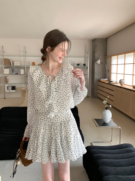 White polka dot long-sleeve dress worn by a model indoors