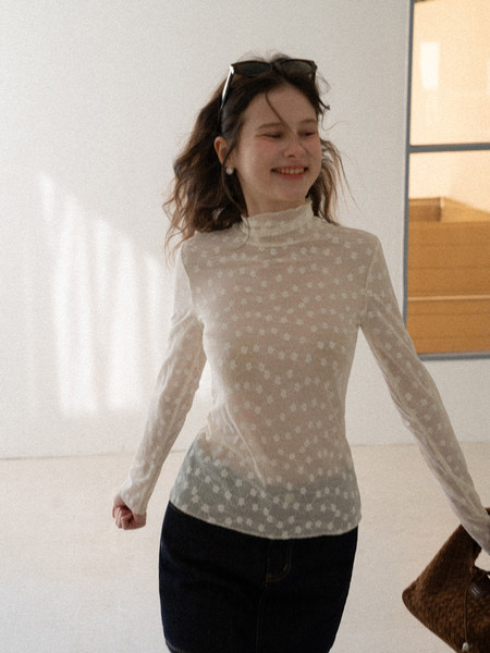 Woman wearing a sheer patterned long-sleeve high-neck top