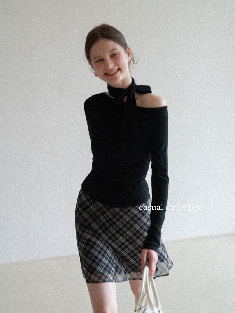 Model wearing a black off-shoulder top with a plaid mini skirt