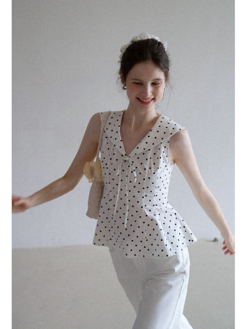 Model wearing a white polka dot sleeveless peplum top