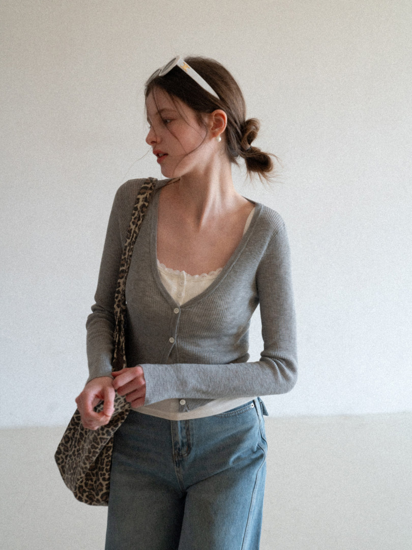 Woman wearing a gray ribbed cardigan over a lace camisole with blue jeans and a leopard print shoulder bag