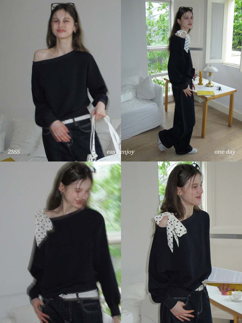 Black off-shoulder sweater top with a white polka-dot bow detail worn by a model