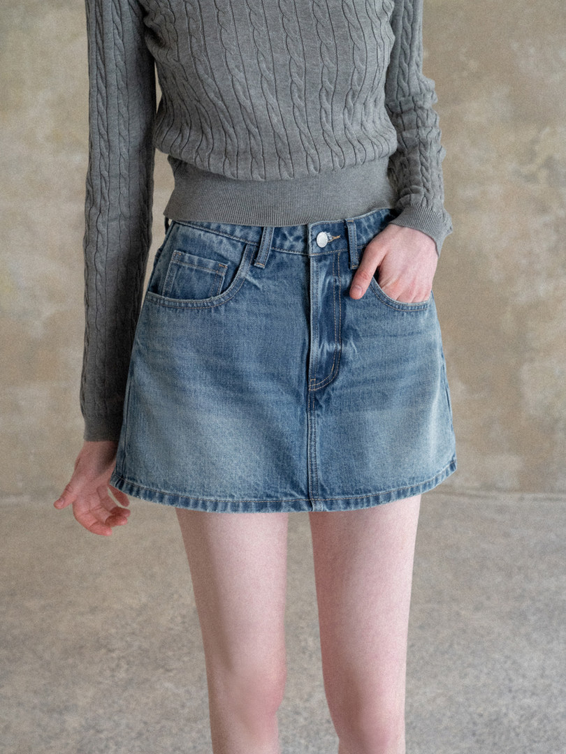 Model wearing a blue denim mini skirt with a gray cable-knit sweater