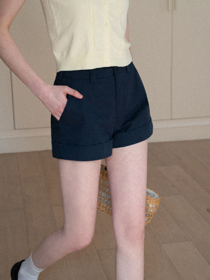 Model wearing navy tailored shorts with a light sleeveless top