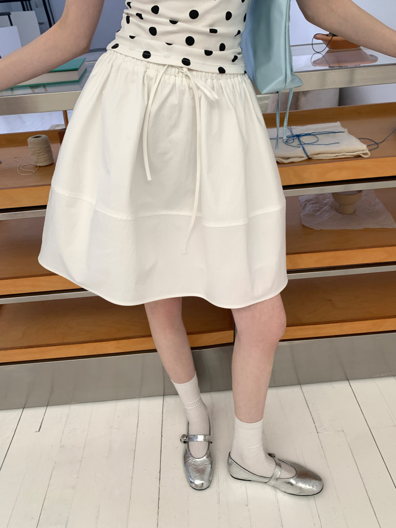 White knee-length skirt worn by a model with a polka dot top