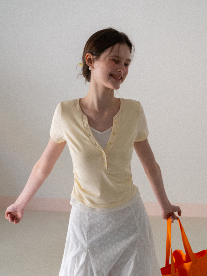 Woman wearing a light yellow short-sleeve button-front top with a white skirt