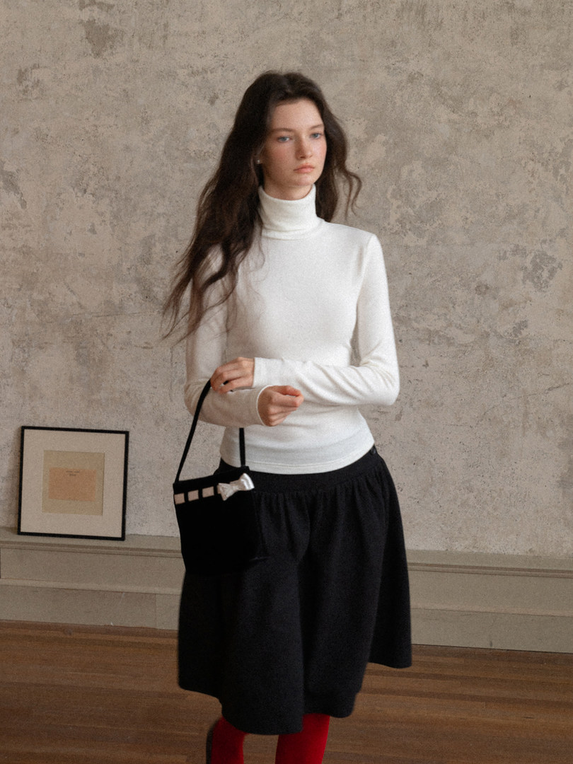 Woman wearing a white turtleneck top with a black skirt