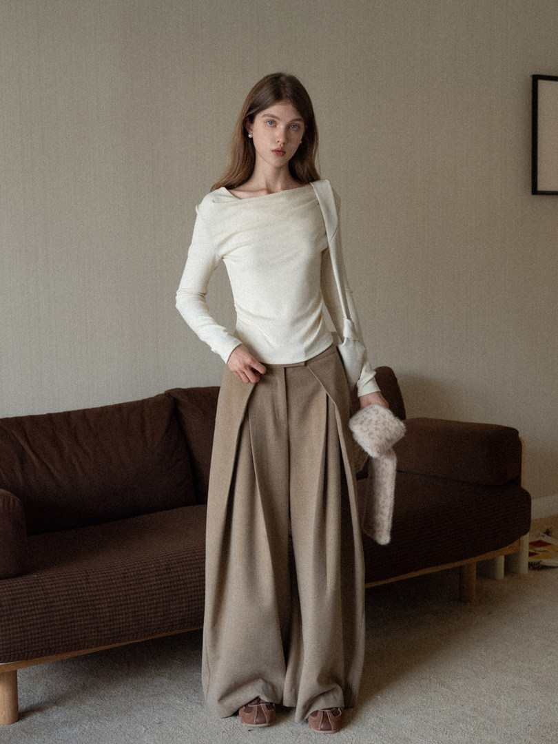 Model wearing a cream long-sleeve top and beige wide-leg trousers