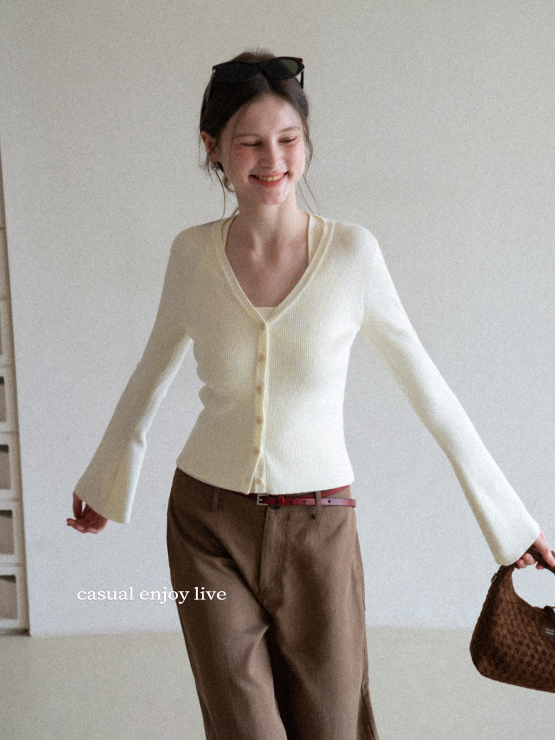 Model wearing a cream knit cardigan with brown trousers