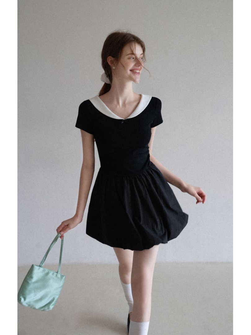 Black short-sleeve mini dress with a white collar worn by a model