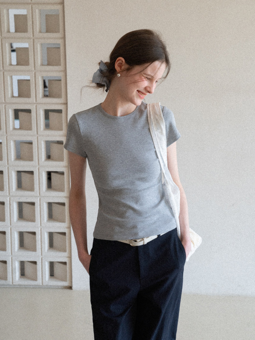 Woman wearing a fitted gray short-sleeve T-shirt with dark pants