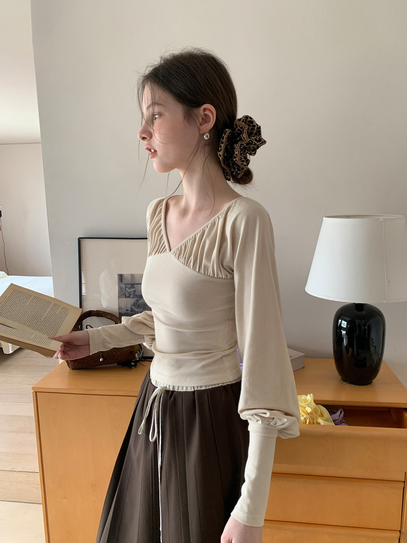 Beige long-sleeve top worn with a dark skirt on a model