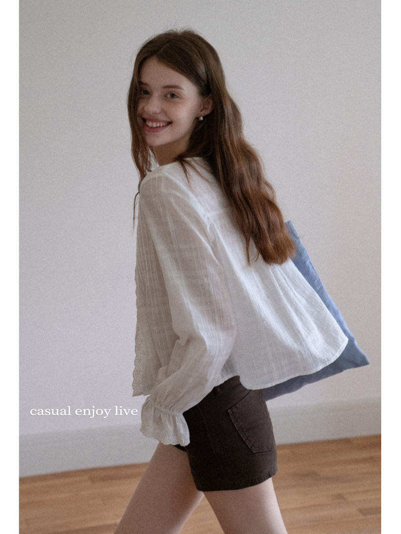 Woman wearing a white lightweight long-sleeve blouse with dark shorts