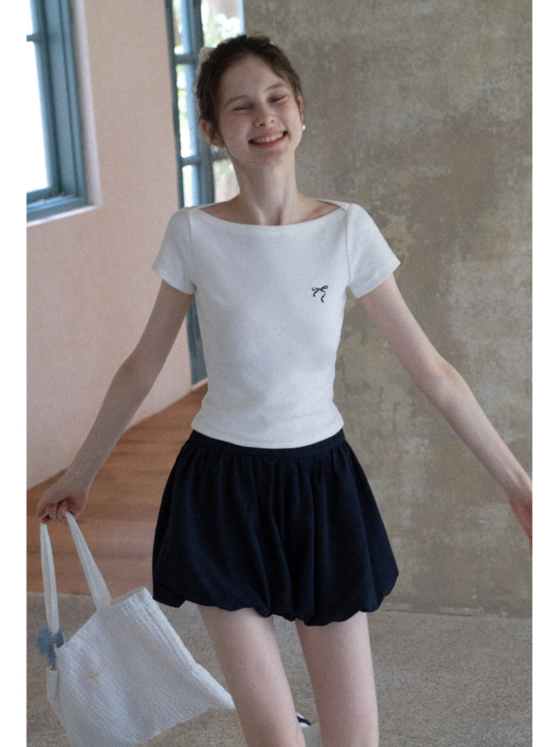 Model wearing a white short-sleeve top with a black skirt indoors