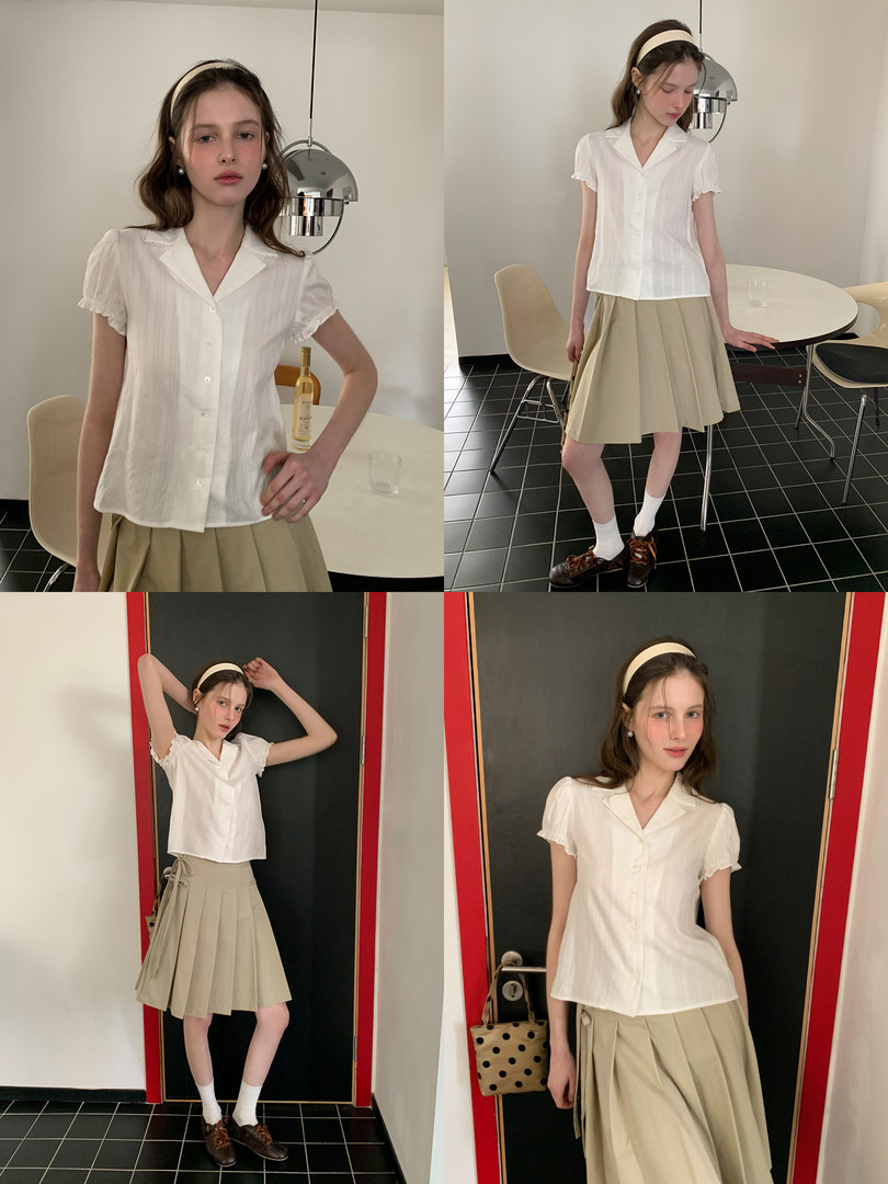 Model wearing a white short-sleeve button blouse with a beige pleated skirt